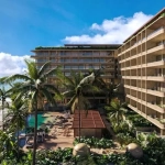 Une façade de deux bâtiments, des palmiers et une piscine avec vue sur l'océan à Inna Beach Condos