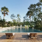 A pool and lounge chairs with gardens around it in Montenia Playa del Carmen