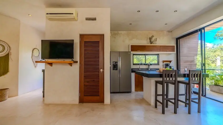 Living room with TV and a kitchen at Casa Caramelo Tulum