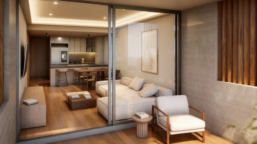 Estancia interior con vista a la terraza que incluye un sofá con cojines, una mesa de centro de madera, un sillón individual, televisión montada en la pared y ventanales corredizos con acceso al exterior de Luum Kan Cancún
