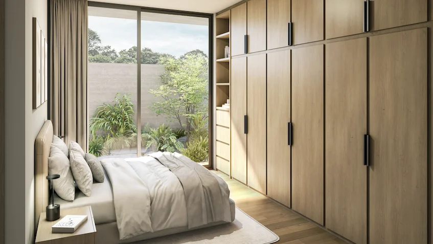 Recámara con vista al jardín que incluye una cama tendida, burós, un clóset amplio de madera y ventanales corredizos con acceso al exterior de Luum Kan Cancún