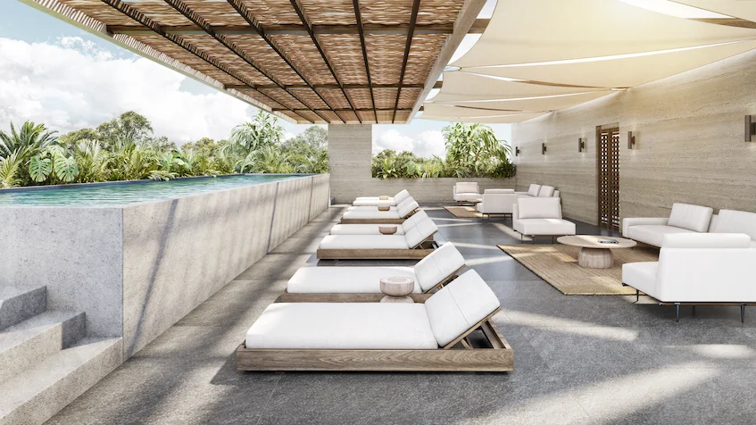 Rooftop con alberca, camastros blancos alineados, salas de descanso exteriores con mesas de centro y pérgola de madera de Luum Kan Cancún