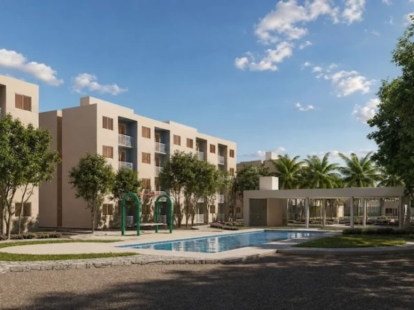 Área de alberca y jardín que incluye una piscina, amplias áreas verdes, un área de juegos infantiles, un edificio residencial de varios niveles, una casa club y árboles de Vía Verde Playa del Carmen,