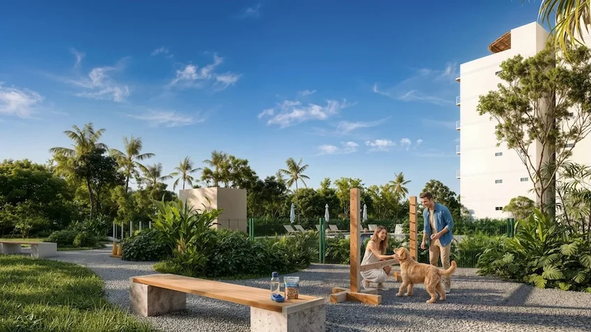 Área para perros que incluye un circuito de agilidad con obstáculos de madera, una banca de concreto, áreas verdes con vegetación tropical y edificios residenciales al fondo de The Origin By Gran Selva Puerto Morelos