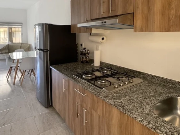 cocina con gabinetes refrigerador mesa rectangular con sillas y un sofá Jardines de Mayakoba Playa del Carmen