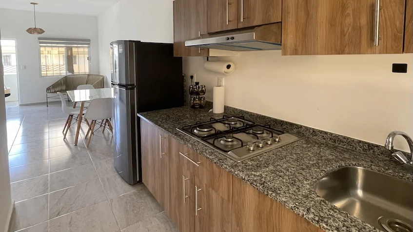 cocina con gabinetes refrigerador mesa rectangular con sillas y un sofá Jardines de Mayakoba Playa del Carmen