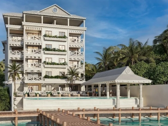 Fachada frontal de un edificio que incluye balcones, ventanas, un área de alberca con estructura techada, palmeras y un muelle de Isola BLU Isla Mujeres.