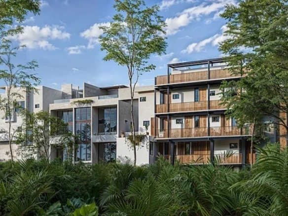 Fachada panorámica que incluye un diseño arquitectónico contemporáneo de varios niveles, acabados de madera, balcones y una vista exterior rodeada de vegetación tropical de Senzik Tulum