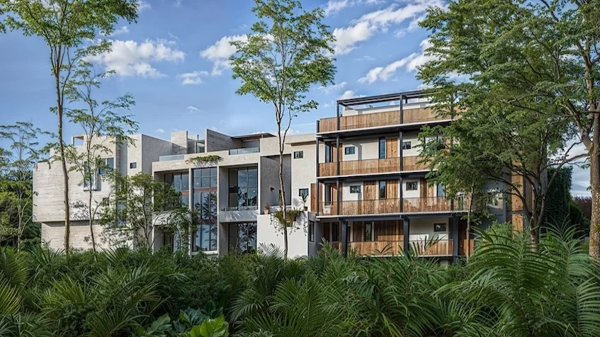 Fachada panorámica que incluye un diseño arquitectónico contemporáneo de varios niveles, acabados de madera, balcones y una vista exterior rodeada de vegetación tropical de Senzik Tulum