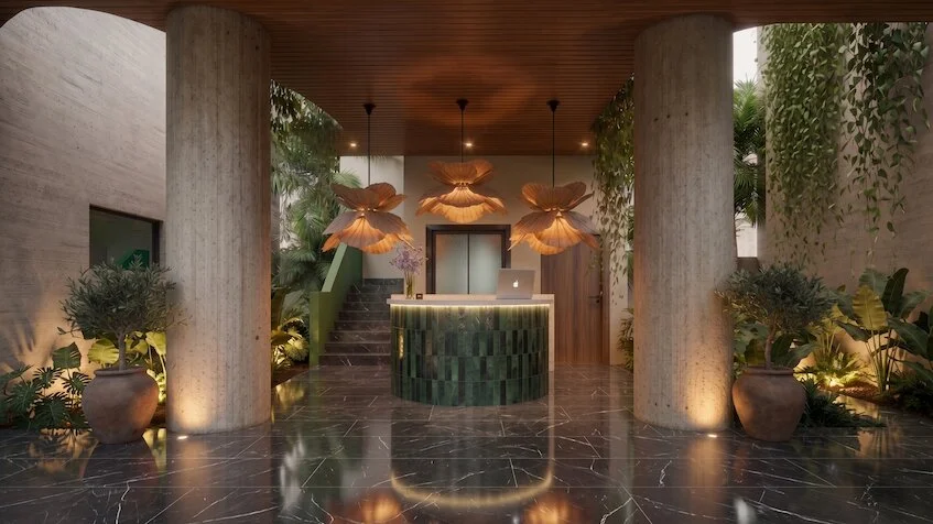 Lobby que incluye un mostrador de recepción con revestimiento verde, columnas circulares, pisos de mármol oscuro reflejante y lámparas colgantes decorativas con diseño floral de Sensum Puerto Morelos