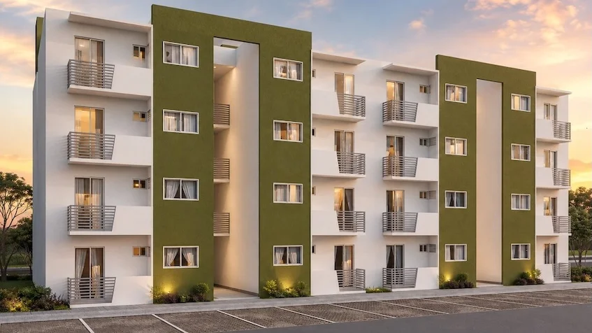 Vista exterior de edificio que incluye una fachada blanca y verde con balcones, un área de estacionamiento, áreas verdes de Vía Verde Playa del Carmen.