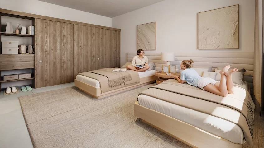 Interior de recámara que incluye dos camas individuales, una cabecera de madera, un buró con lámpara, un vestidor abierto al fondo y una decoración textil en la pared de The Reserve By Gran Selva Puerto Morelos.