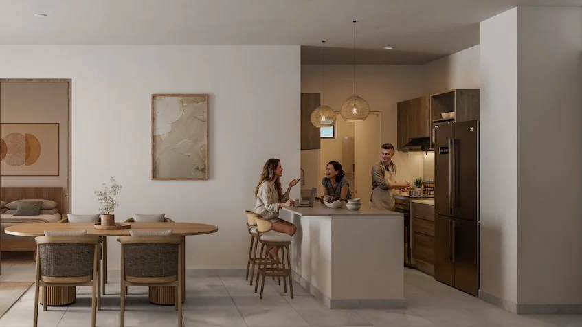 Vista interior que incluye una cocina abierta, un comedor con mesa ovalada de madera y tres sillas, además de una barra con periqueras