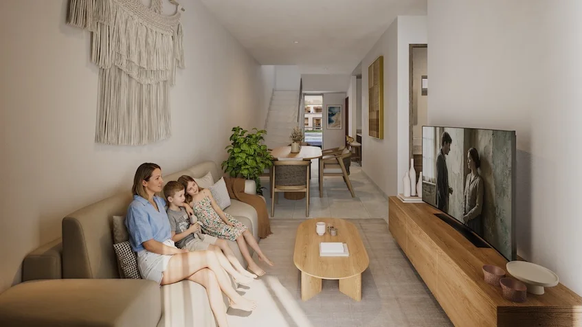 Vista interior que incluye una sala de estar con un sofá beige, una mesa de centro de madera, un mueble de televisión alargado, un área de comedor al fondo y decoración de pared de The Origin by Gran Selva Puerto Morelos.