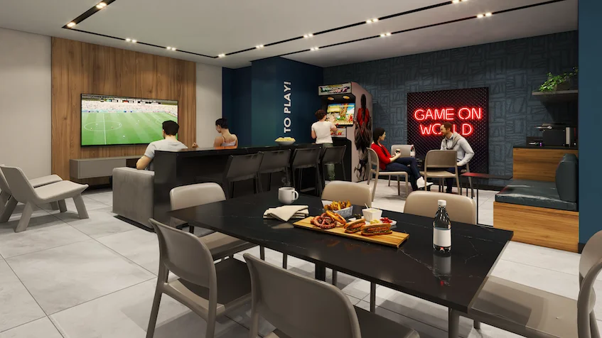 Sala de juegos comunitaria que incluye una mesa de comedor oscura con sillas y aperitivos, una zona de televisión con sillones y pantallas, máquinas de videojuegos recreativos con carteles luminosos, un muro decorativo con un letrero que dice "GAME ON WORLD" y detalles de madera y concreto de KUN 21° 86° Cancún