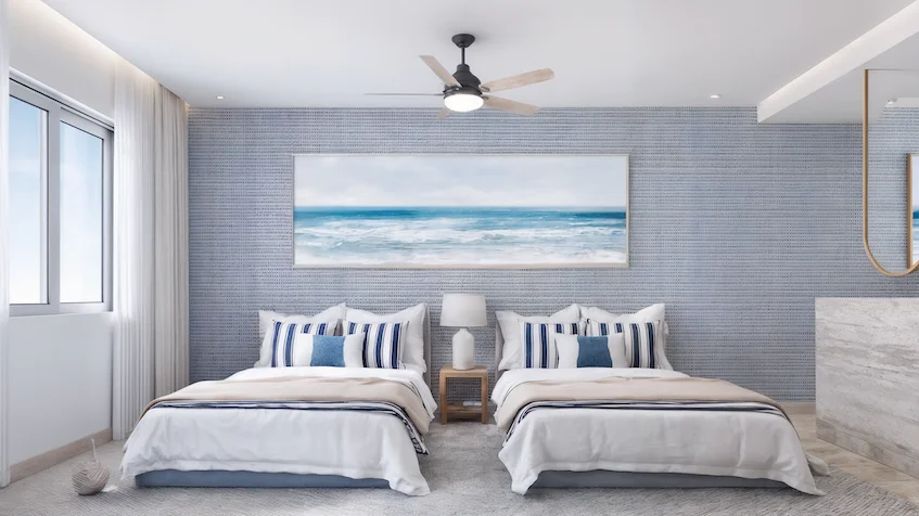 Diseño interior de la recámara que incluye dos camas, un buró con lámpara, un ventilador de techo, además de un mueble con espejo de Isola BLU Isla Mujeres.