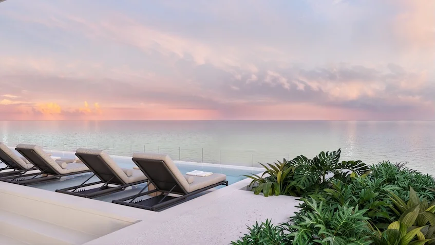 Elegante terraza con alberca infinity, camastros y vegetación tropical frente a un mar en calma al atardecer de Village Blu Puerto Morelos